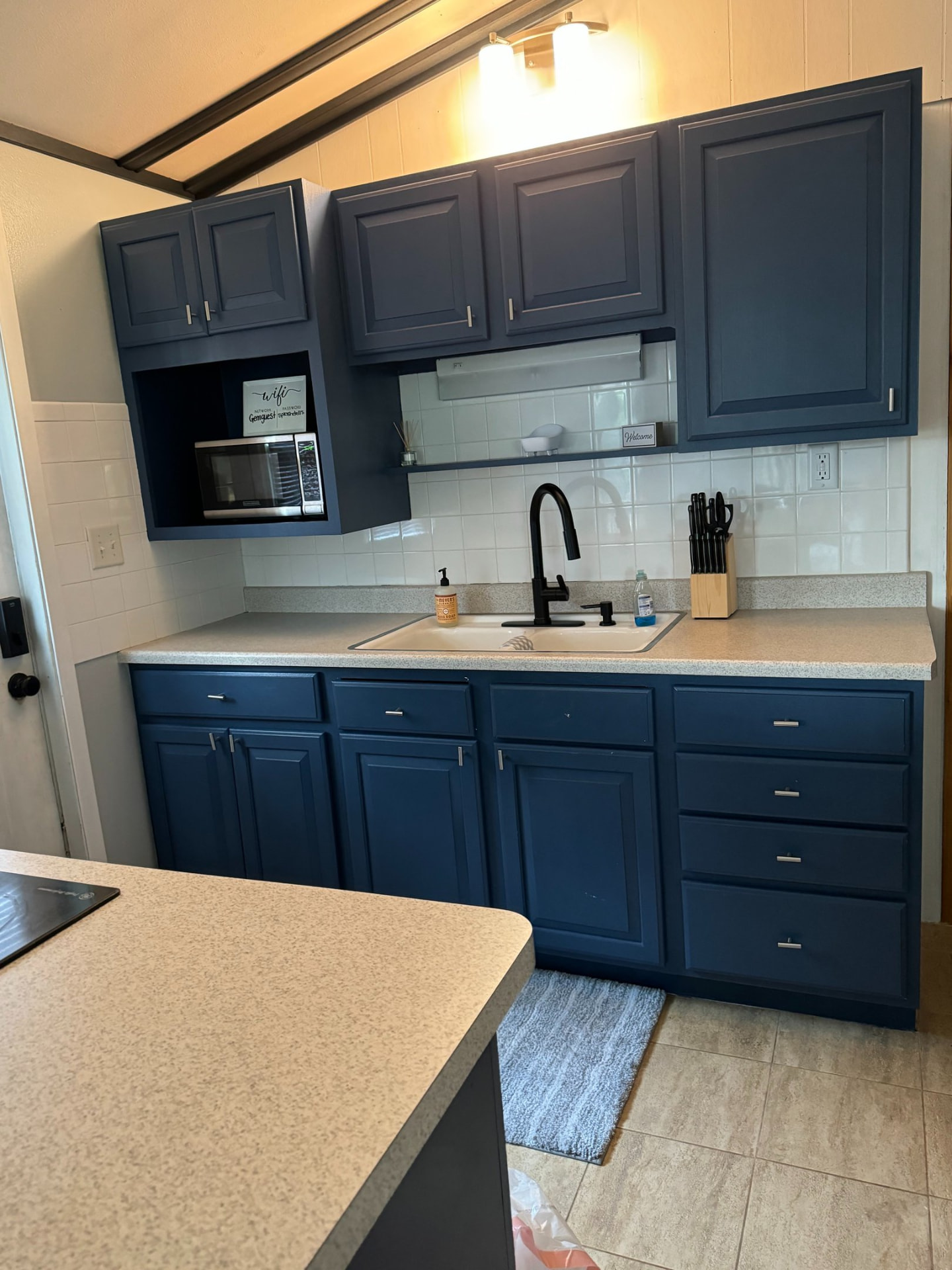 Clean vacation rental kitchen with navy cabinets and white tile backsplash