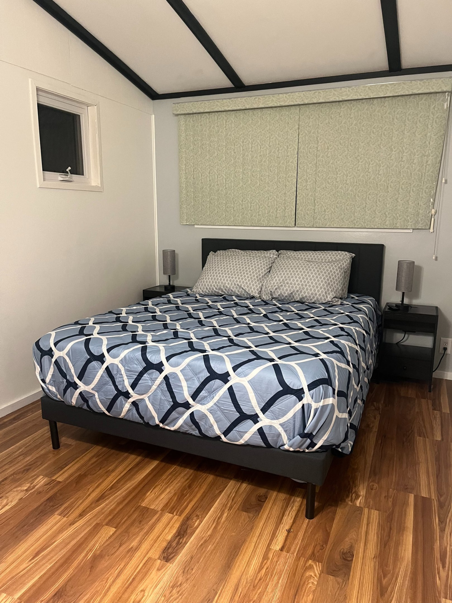 Guest bedroom with navy patterned bedding and dark wood bed frame, ready for check-in