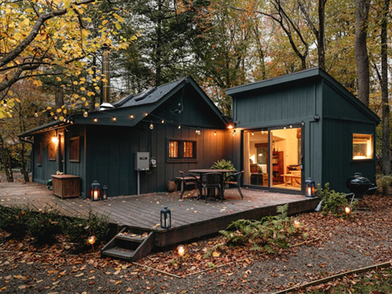 Dark green vacation cabin surrounded by autumn trees, ready for arriving guests