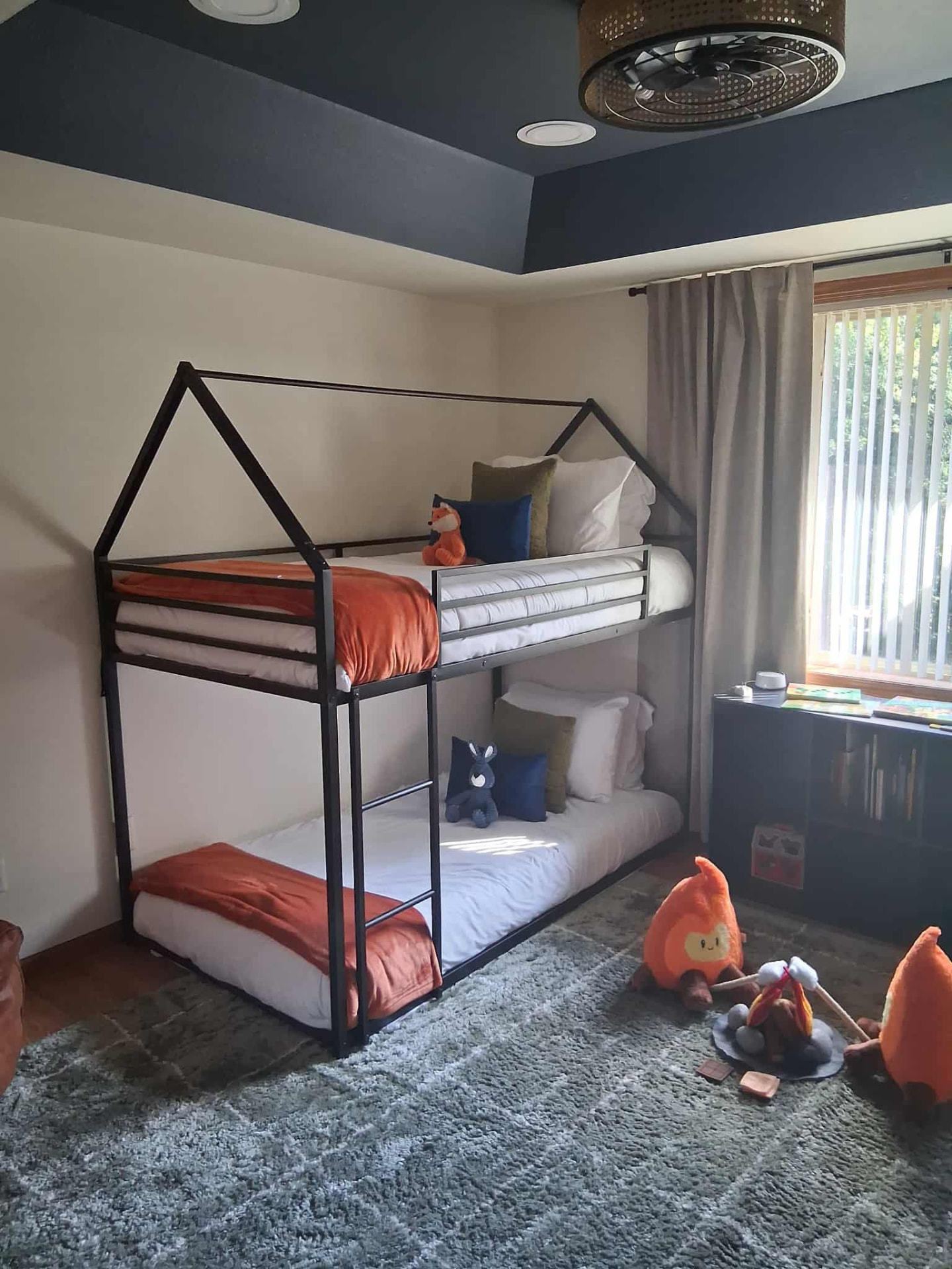 Children's guest room with house-frame bunk beds and neatly arranged bedding