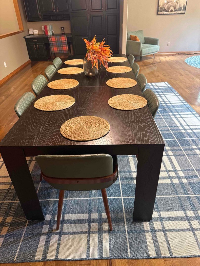 Dining room with a long dark table set with woven placemats and an autumn centerpiece