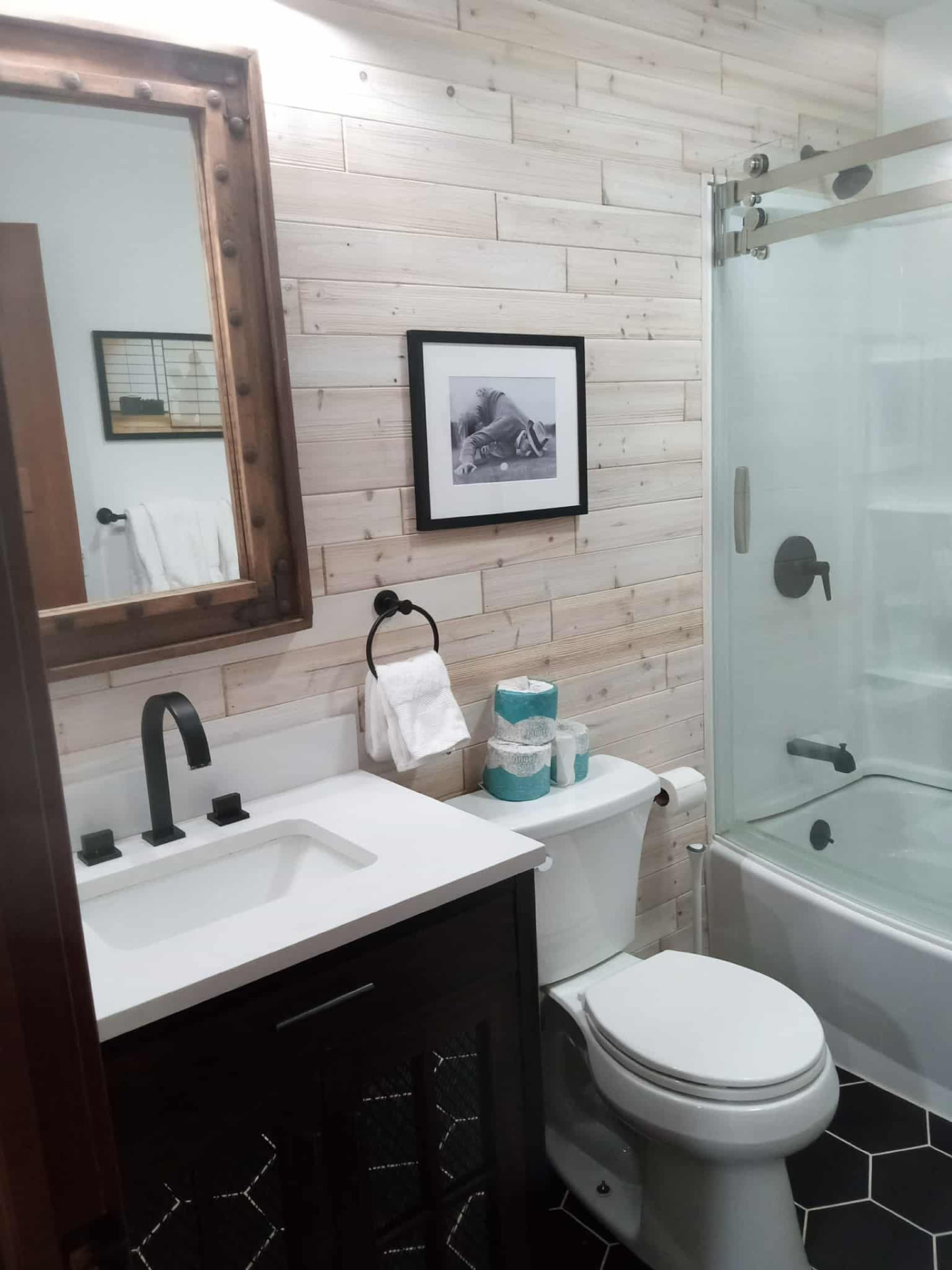Bright bathroom with a glass shower, white vanity, and wood-plank accent wall