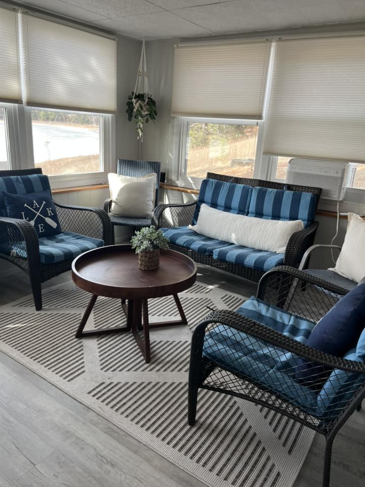 Lake-view sitting room with blue-cushioned wicker seating arranged around a round table