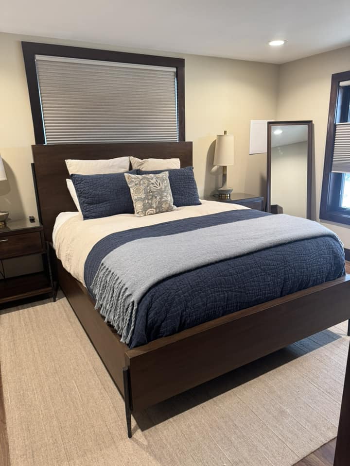 Guest bedroom with navy bedding, dark wood furniture, and neatly arranged pillows